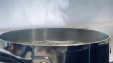Pürüzsüz bir sobanın üstünde kaynayan bir su tenceresinden çıkan buhar sıcaklığı, sadeliği ve ev yemeği sanatını çağrıştırıyor.