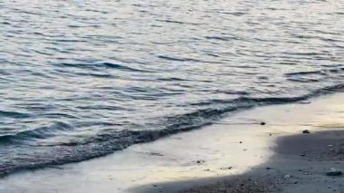 Yumuşak dalgalar kumlu sahile dokunur, sakin ve rahatlatıcı bir sahne yaratır. Su kenarında rahatlama ve yansıma için mükemmeldir.