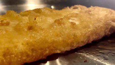 Kıtır kıtır altın renginde balık usulca cızırdar, geleneksel ve rahatlatıcı İngiliz yemeğinin özünü somutlaştırır, İngiliz balık ve patates kızartması.