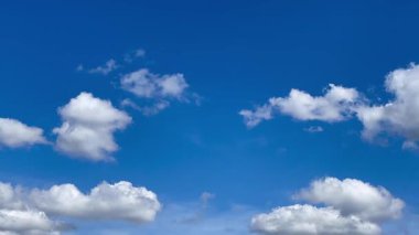 Pofuduk beyaz bulutlarla bezenmiş parlak mavi gökyüzü, sakin ve açık bir atmosfer yaratıyor. Açık hava rahatlığı ve manzara için mükemmel.