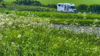 Eastbourne, Doğu Sussex, Birleşik Krallık yakınlarındaki manzaralı İngiliz kırsalına park etmiş, yemyeşil tarlalar, kır çiçekleri ve sakin sahil şeridine bakan karavan.