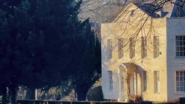 Gürcistan tarzı zarif kır evi ağaçlarla çerçevelenmiş, altın güneş ışığıyla yıkanmış ve sakin bir kırsal alanda kurulmuş.