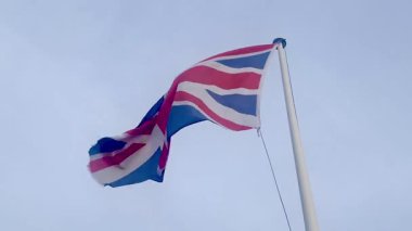 Birleşik Krallık 'ın İngiliz bayrağı yumuşak, bulutlu gökyüzüne el sallıyor. İngiliz mirasını ve gururunu simgeliyor.