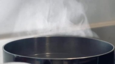 Pürüzsüz bir sobanın üstünde kaynayan bir su tenceresinden çıkan buhar sıcaklığı, sadeliği ve ev yemeği sanatını çağrıştırıyor.