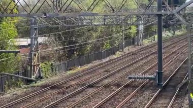 Uzağa uzanan demiryolu rayları, bereketli yeşillik ve ağaçlar tarafından çerçevelenmiş, kırsal alanda İngiliz mirası, yavaş çekim