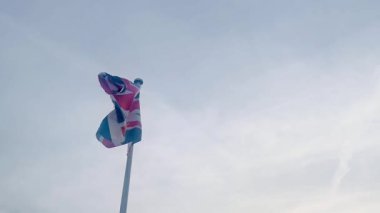 Birleşik Krallık 'ın İngiliz bayrağı yumuşak, bulutlu gökyüzüne el sallıyor. İngiliz mirasını ve gururunu simgeliyor.
