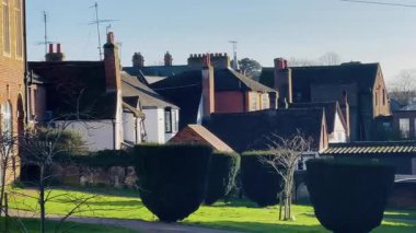 Tuğla ve pastel renkli ön cepheleri olan geleneksel İngiliz evleriyle dolu bir cadde. Mimari açık mavi altında zarif pencereler, perdeli çatılar ve dekoratif ayrıntılar vurguluyor