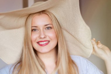 Kadın, moda ve yaz country cazibesi, sarışın güzellik ve geniş kenarlı plaj şapkalı zarafet. Kadınsı cazibe, zamansız tarz ve zarif parıltı. Gülümse, hasır şapka ve mavi çizgili bluz, doğal.