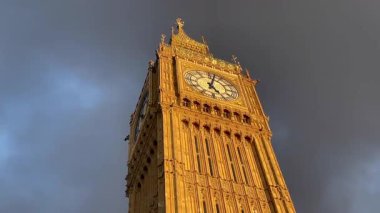 Londra, Westminster 'ın göbeğinde Büyük Ben alacakaranlıkta aydınlandı, dramatik bir gökyüzüne karşı altın parıltı