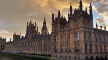 Westminster Sarayı altın günbatımı renkleriyle yıkandı. Gotik silueti Thames Nehri boyunca dramatik bir şekilde yükseldi.