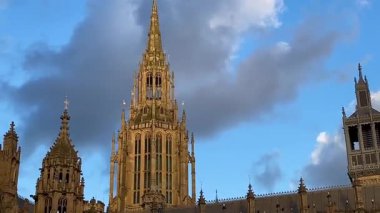 Westminster Sarayı, Westminster, Londra 'daki Parlamento Binası, altın ışık süslü gotik cepheye dramatik gölgeler seriyor.