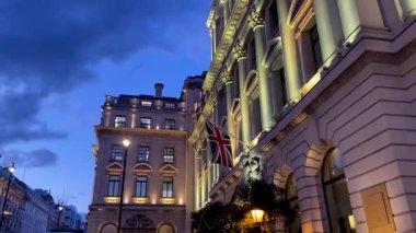 Sendika Jack 'in alacakaranlıkta kanat çırpmasıyla aydınlanan tarihi binalar, Londra' nın derin mavi gökyüzüne yumuşak bir altın parıltı saçıyor.