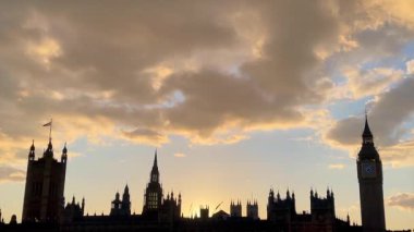 Gün batımında Parlamentonun Siluetli Evleri ve Büyük Ben 'i, Westminster, Londra' daki Thames Nehri 'ne yansıtan altın ışıkla
