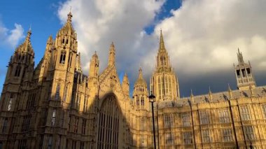 Westminster Sarayı, Westminster, Londra 'daki Parlamento Binası, altın ışık süslü gotik cepheye dramatik gölgeler seriyor.