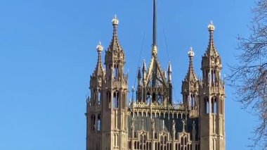 İngiliz bayrağı, Westminster, Londra 'daki açık mavi gökyüzünün altında Parlamento Binaları' nın detaylı bir kulesinde dalgalanıyor.
