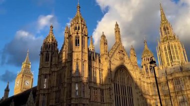 Westminster Sarayı, Westminster, Londra 'daki Parlamento Binası, altın ışık süslü gotik cepheye dramatik gölgeler seriyor.