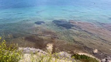 Sığ turkuaz sular, Türkiye 'nin Bodrum kenti yakınlarındaki kayalık bir kıyıda yavaşça süzülüyor. Su altı taşları açıkça görülüyor, yavaş çekim..
