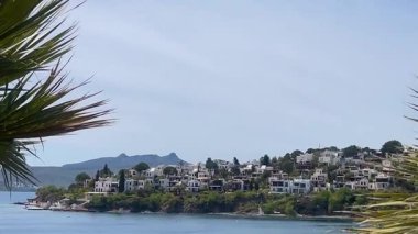 Beyazlatılmış villalar, Türkiye 'nin Bodrum kenti yakınlarındaki sakin Ege Denizi' nin üzerinde kayalık bir yarımadadan öteye yükselen dağlarla birlikte, ağır çekimde ilerliyorlar..