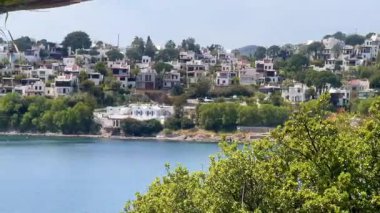 Beyazlatılmış villalar, Türkiye 'nin Bodrum kenti yakınlarındaki sakin Ege Denizi' nin üzerinde kayalık bir yarımadadan öteye yükselen dağlarla birlikte, ağır çekimde ilerliyorlar..