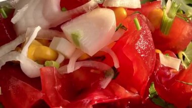 Canlı, mavi bir kasede servis edilen domates, soğan, marul ve limon dilimlerinden oluşan taze bir Akdeniz salatası..