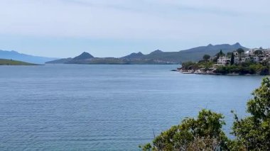 Beyazlatılmış villalar, Türkiye 'nin Bodrum kenti yakınlarındaki sakin Ege Denizi' nin üzerinde kayalık bir yarımadadan öteye yükselen dağlarla birlikte, ağır çekimde ilerliyorlar..
