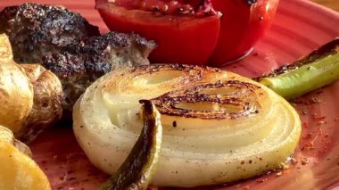 Kızarmış sebzeler, domatesler ve soğan ile pişirilmiş sulu biftek. Köy tabaklarında bol soslu, ağır çekimde..