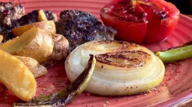 Kızarmış sebzeler, domatesler ve soğan ile pişirilmiş sulu biftek. Köy tabaklarında bol soslu, ağır çekimde..