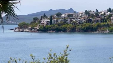 Beyazlatılmış villalar, Türkiye 'nin Bodrum kenti yakınlarındaki sakin Ege Denizi' nin üzerinde kayalık bir yarımadadan öteye yükselen dağlarla birlikte, ağır çekimde ilerliyorlar..