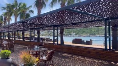 Türkiye 'nin Bodrum kenti yakınlarındaki sahil kafeteryasında gölgeli koltuklar, deniz manzarası ve örülmüş kubbelerin altında rahat bir açık hava ortamı bulunuyor.