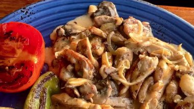 Türkiye 'nin Bodrum kenti yakınlarında mavi bir seramik tabakta altın patates ve ızgara sebze ile servis edilen kremalı mantar soslu yumuşak tavuk..