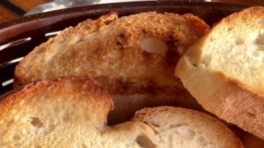 Taze kızarmış ekmeğin altın dilimleri gevrek kabuklu ve havadar kırıntılarıyla sıcak, yavaş çekimde servis edilir..