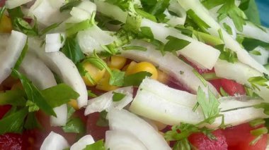 Canlı, mavi bir kasede servis edilen domates, soğan, marul ve limon dilimlerinden oluşan taze bir Akdeniz salatası..