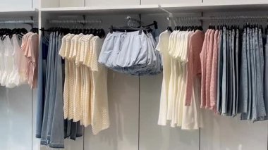 Butik elbise vitrinleri, ahşap askılar ve zarif tasarım, hızlı moda konsepti, yavaş çekim, ahşap raflarda desenli kadın modası sergileniyor.