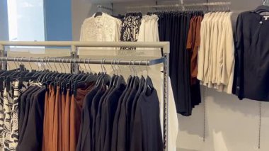 Butik elbise vitrinleri, ahşap askılar ve zarif tasarım, hızlı moda konsepti, yavaş çekim, ahşap raflarda desenli kadın modası sergileniyor.