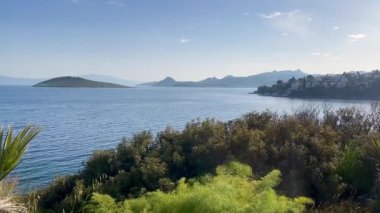 Türkiye 'nin Bodrum kenti yakınlarındaki Ege Denizi, ufuk boyunca uzanan adalar ve burunlar yemyeşil, yavaş çekim