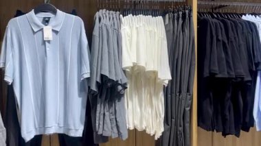 Akıllı gömlekler ve klasik tonda pantolonlar erkek giyim mağazasında ahşap bir duvara, hızlı moda konseptine, yavaş çekim fikrine karşı düzgünce asılıdır.