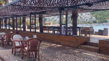 Türkiye 'nin Bodrum kenti yakınlarındaki sahil kafeteryasında gölgeli koltuklar, deniz manzarası ve örülmüş kubbelerin altında rahat bir açık hava ortamı bulunuyor.