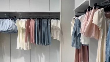 Butik elbise vitrinleri, ahşap askılar ve zarif tasarım, hızlı moda konsepti, yavaş çekim, ahşap raflarda desenli kadın modası sergileniyor.