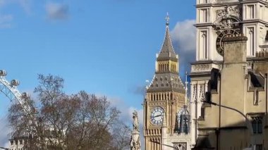 Büyük Ben, Londra Gözü ve Westminster Manastırı Londra 'nın merkezinde tarihi binalar ve çıplak kış ağaçları tarafından çerçevelenmiş parlak bir gökyüzünün altında.