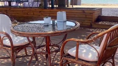 Türkiye 'nin Bodrum kentindeki ahşap bir gölgeliğin altında, portatif sandalyeli ve cam kapaklı bir kafeterya masası.
