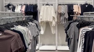 Butik elbise vitrinleri, ahşap askılar ve zarif tasarım, hızlı moda konsepti, yavaş çekim, ahşap raflarda desenli kadın modası sergileniyor.