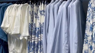 Butik elbise vitrinleri, ahşap askılar ve zarif tasarım, hızlı moda konsepti, yavaş çekim, ahşap raflarda desenli kadın modası sergileniyor.