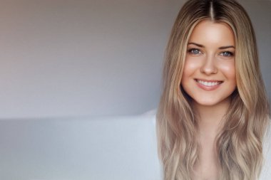 Laptop yaşam tarzı ve evden çalışma, internet kursu, bilgisayar kullanan uzun dalgalı saçlı sarışın kadın, doğal makyaj ve mavi gözler, dijital yaşam dengesi.