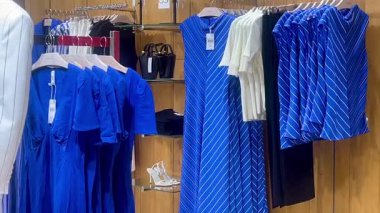 Butik elbise vitrinleri, ahşap askılar ve zarif tasarım, hızlı moda konsepti, yavaş çekim, ahşap raflarda desenli kadın modası sergileniyor.