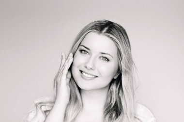 Doğal güzellik, cilt bakımı ve kozmetik, gülümseyen sarışın kadın mavi gözlü ve parlak yüzlü nemlendirici kullanan, hafif klasik tek renkli portre