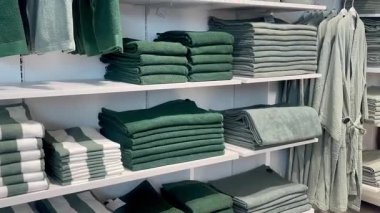 Sabun makineleri ve aksesuarlarla düzgünce dizilmiş havlular bir çarşaf dükkanında beyaz raflar, yavaş çekim.