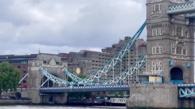 Londra 'daki Tower Bridge' in görkemli bir yakın görüntüsü, Thames Nehri 'nin üzerinde dramatik bulutların altında cesurca duruyor, değerli bir İngiliz ikonu, yavaş çekim