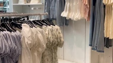 Butik elbise vitrinleri, ahşap askılar ve zarif tasarım, hızlı moda konsepti, yavaş çekim, ahşap raflarda desenli kadın modası sergileniyor.