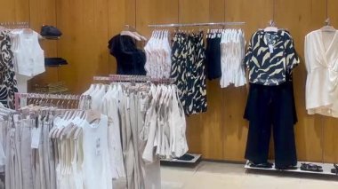 Butik elbise vitrinleri, ahşap askılar ve zarif tasarım, hızlı moda konsepti, yavaş çekim, ahşap raflarda desenli kadın modası sergileniyor.