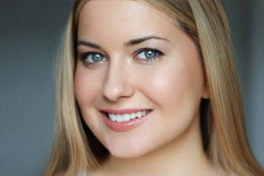 Doğal güzellik ve sağlıklı beyaz dişler, 30 'lu yaşlarında, gülümseyen sarışın bir kadının yakından çekilmiş portresi mavi gözlü, parlak tenli, gösterişli cilt bakımı ve yüz güzelliği.